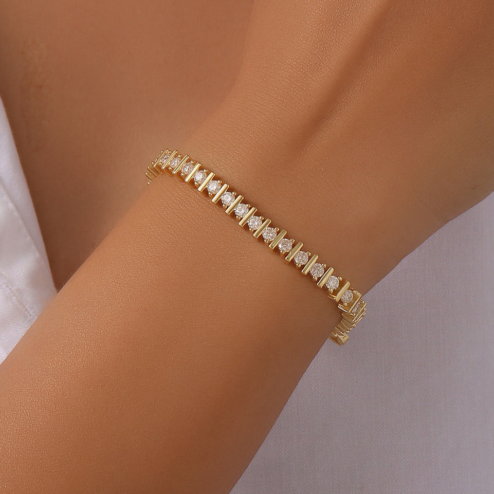 Gold bracelet on a person's wrist with a plain background