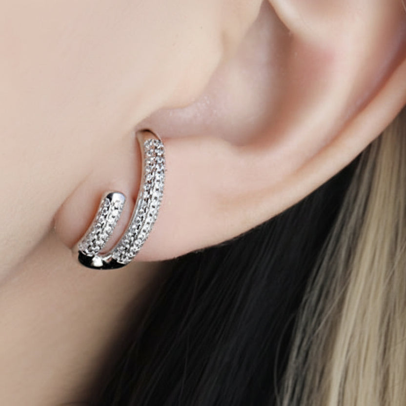 Close-up of an ear wearing a silver hoop earring with a white background