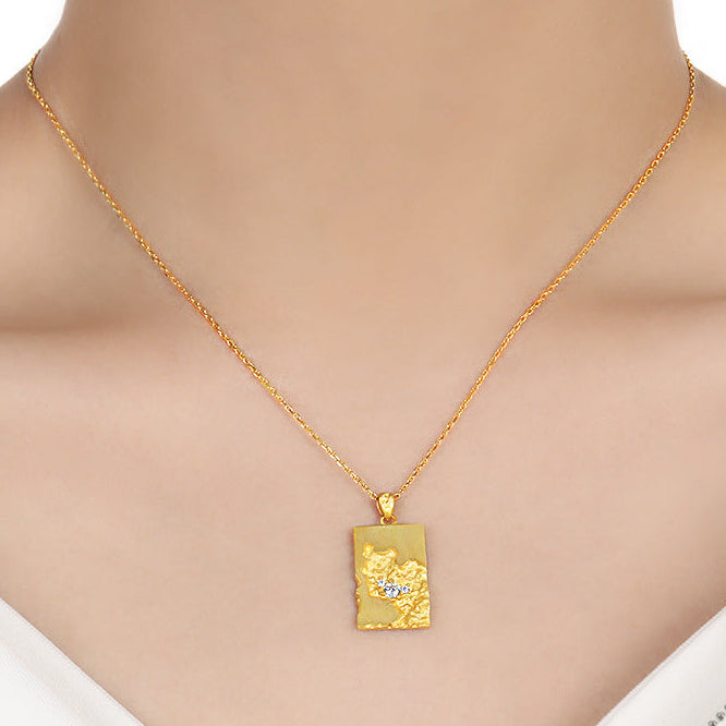 Tag portrait bar Gold necklace with a pendant on a mannequin wearing a white top.