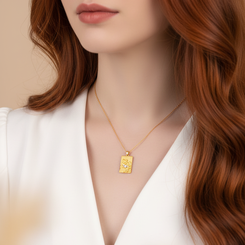 Woman wearing a gold necklace with a pendant against a neutral background