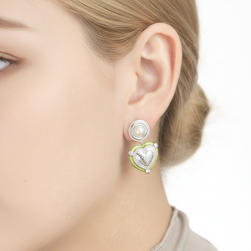 Close-up of an ear wearing a decorative earring with a pearl and green gemstone.