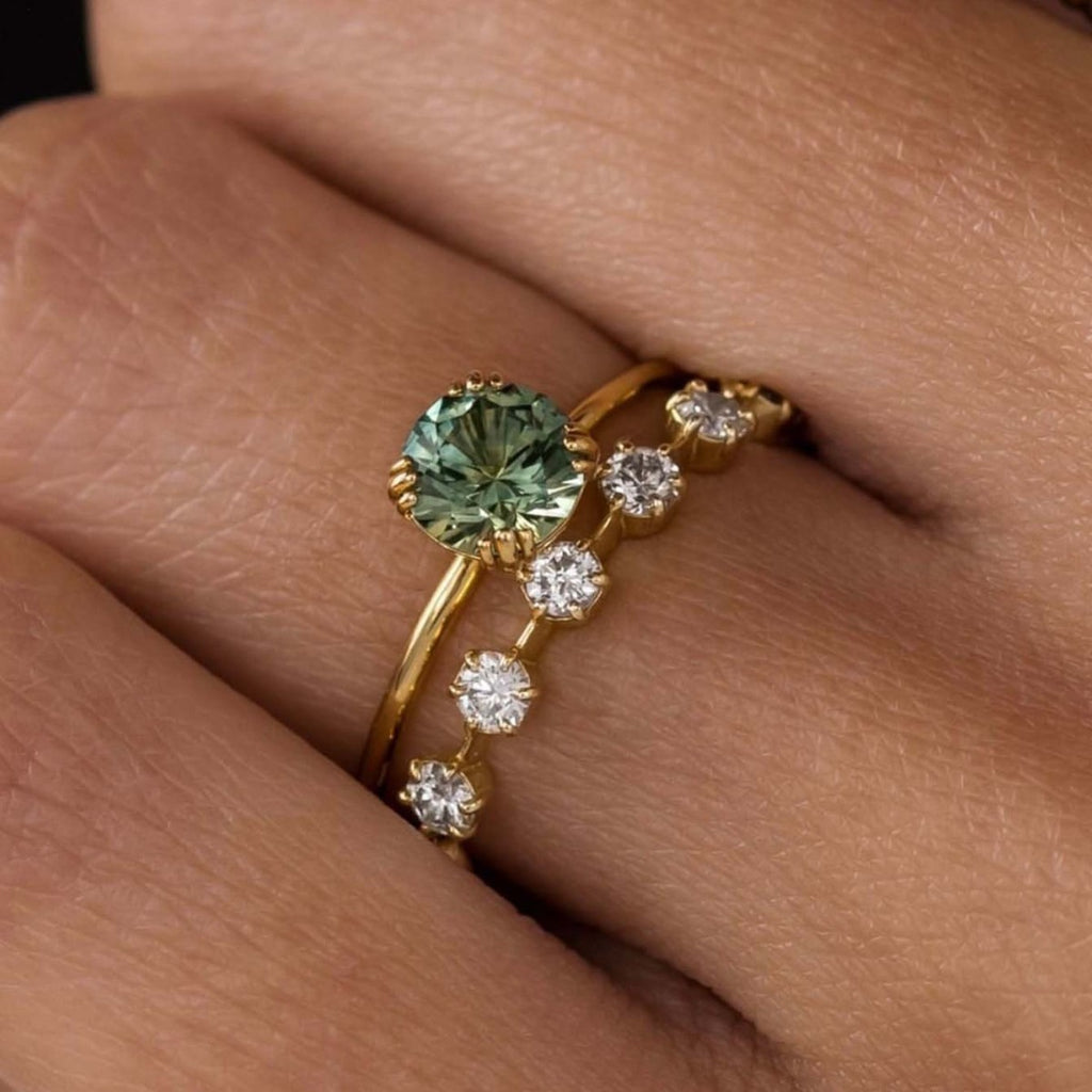 Gold ring with a green gemstone on a person's finger