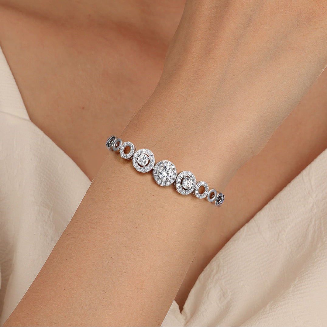 Silver bracelet with round stones on a wrist against a neutral background