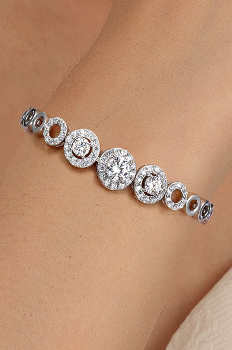A close-up of a silver-toned bracelet with multiple round pavé-set clear stones worn on a person's wrist.