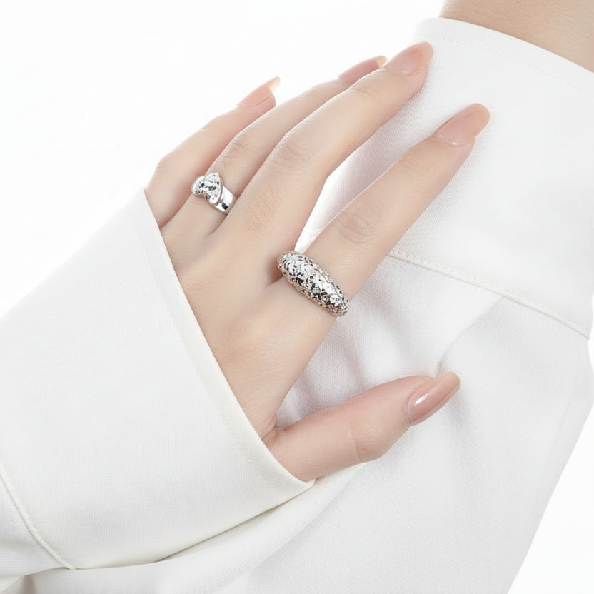 Hand wearing two silver rings with a plain background