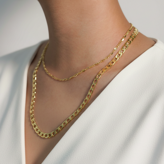Gold chain necklace on a person wearing a white top against a neutral background
