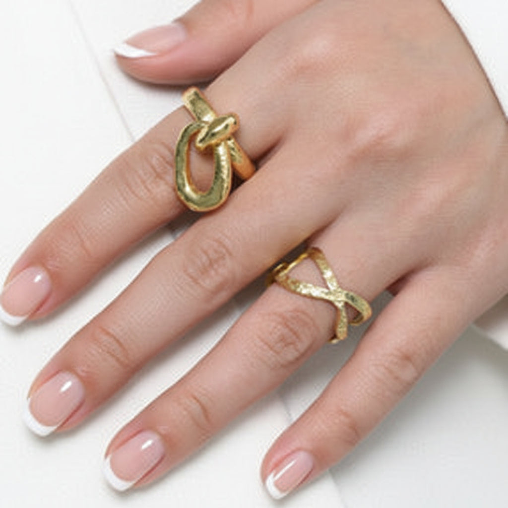 Close-up of a hand wearing gold rings on a neutral background.