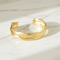 A gold-coloured open bangle bracelet with irregular folds, lalors jewellery