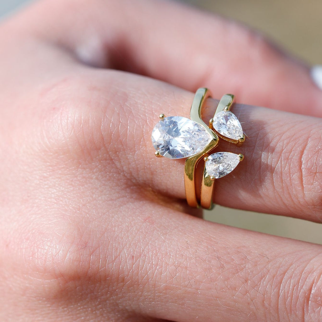 Gold ring with pear-shaped gemstones on a finger