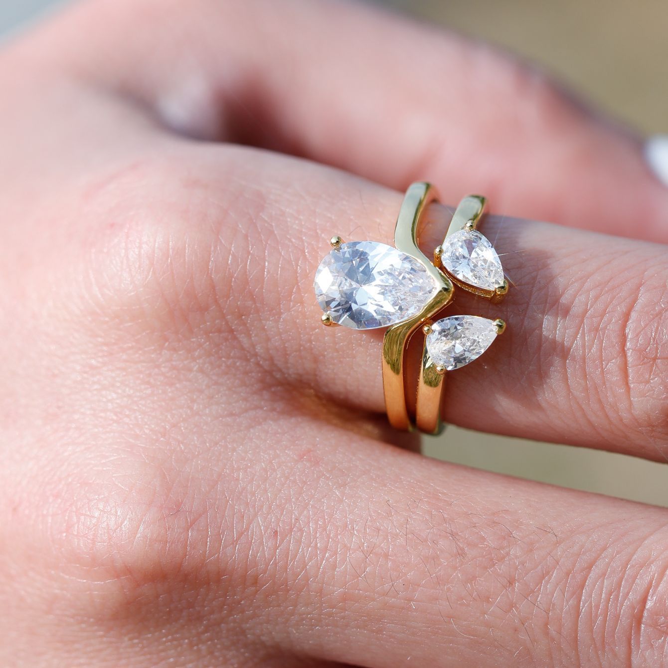 Gold ring with pear-shaped gemstones on a finger