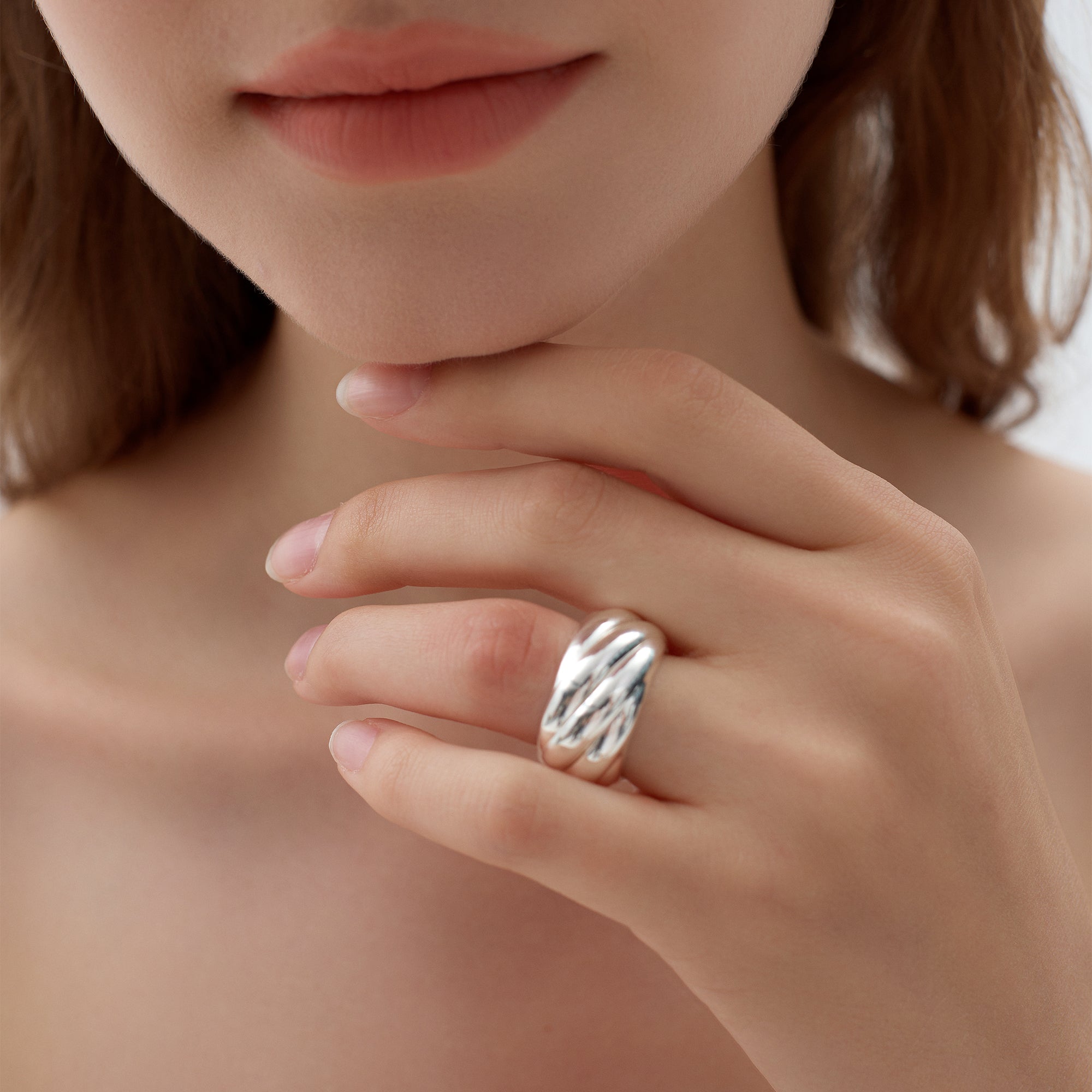 Close-up of a hand wearing a silver ring with a blurred background