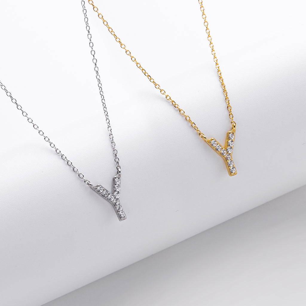 Two necklaces, one gold and one silver, with a 'V' shape on a light gray background.
