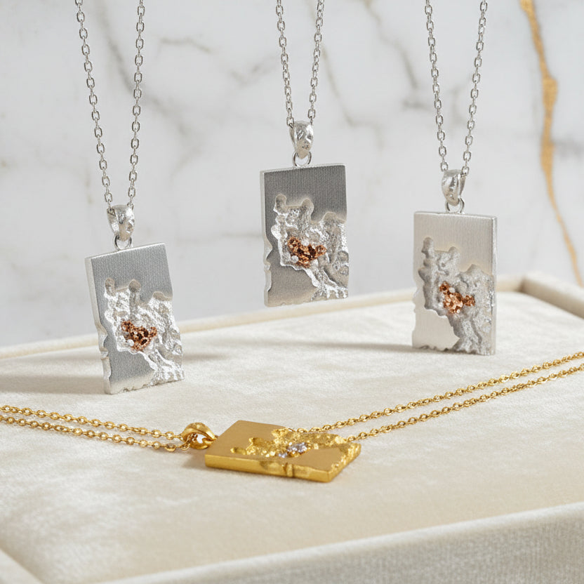 Three necklaces with unique pendants on a white and gold marble surface