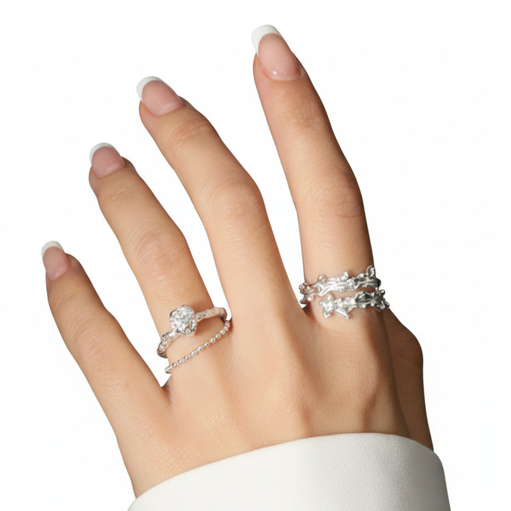 Hand wearing two silver rings with a black background