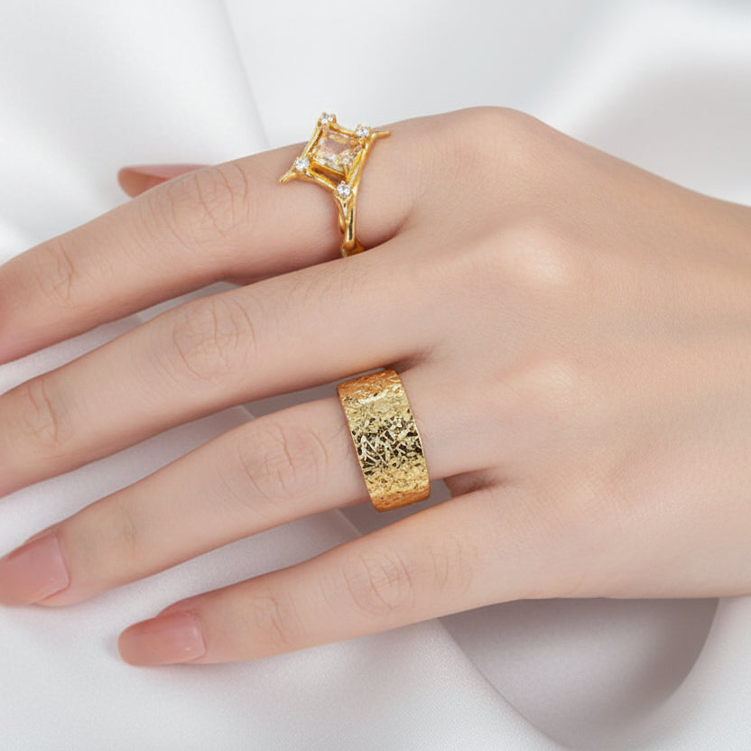 Hand wearing two gold rings on a black background