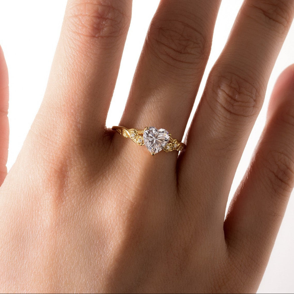 Gold ring with a diamond on a hand against a white background