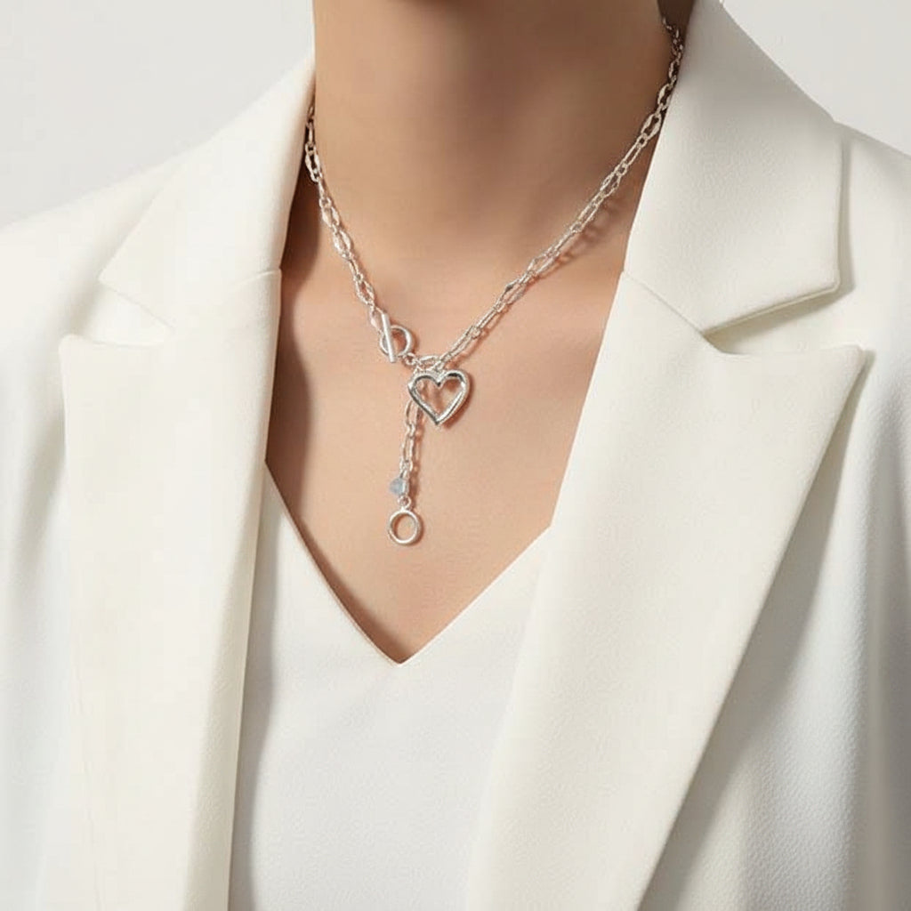 Silver necklace with heart and key pendant worn by a person