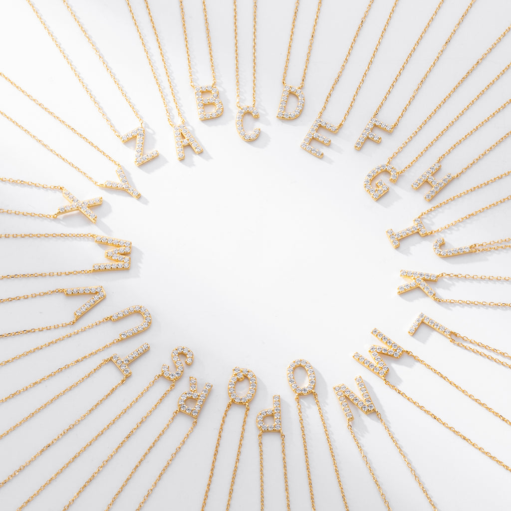 Gold necklaces with letters spelling out a name on a white background