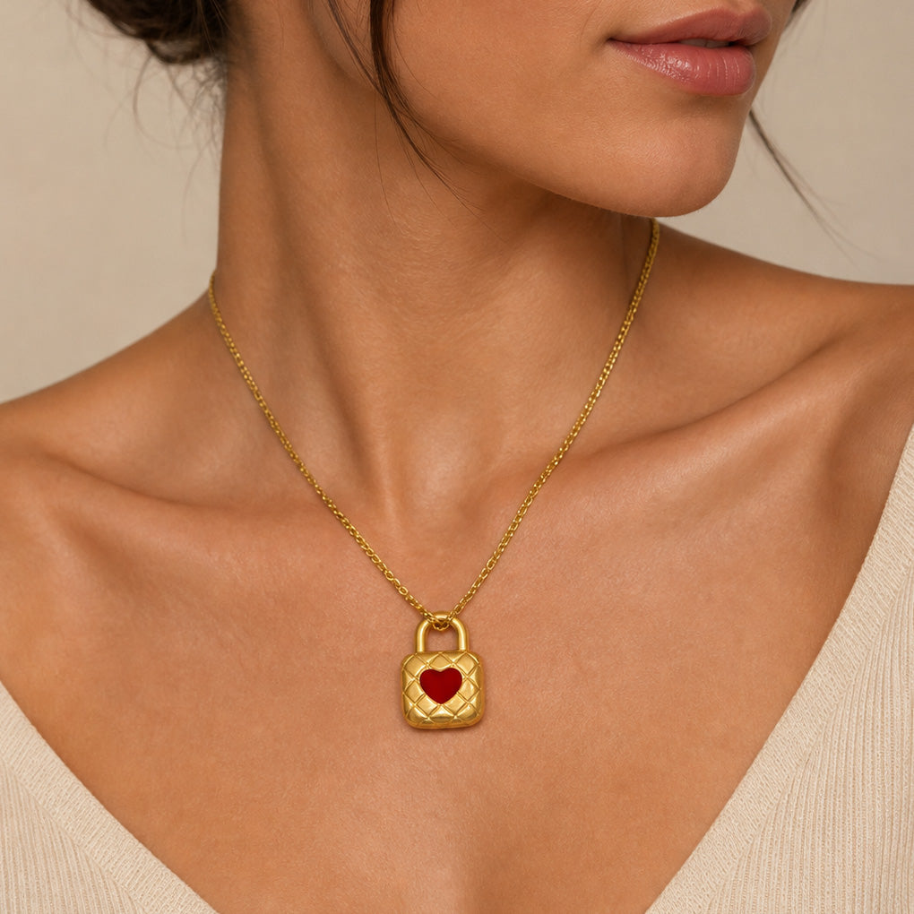 Gold necklace with a heart-shaped lock pendant on a neutral background