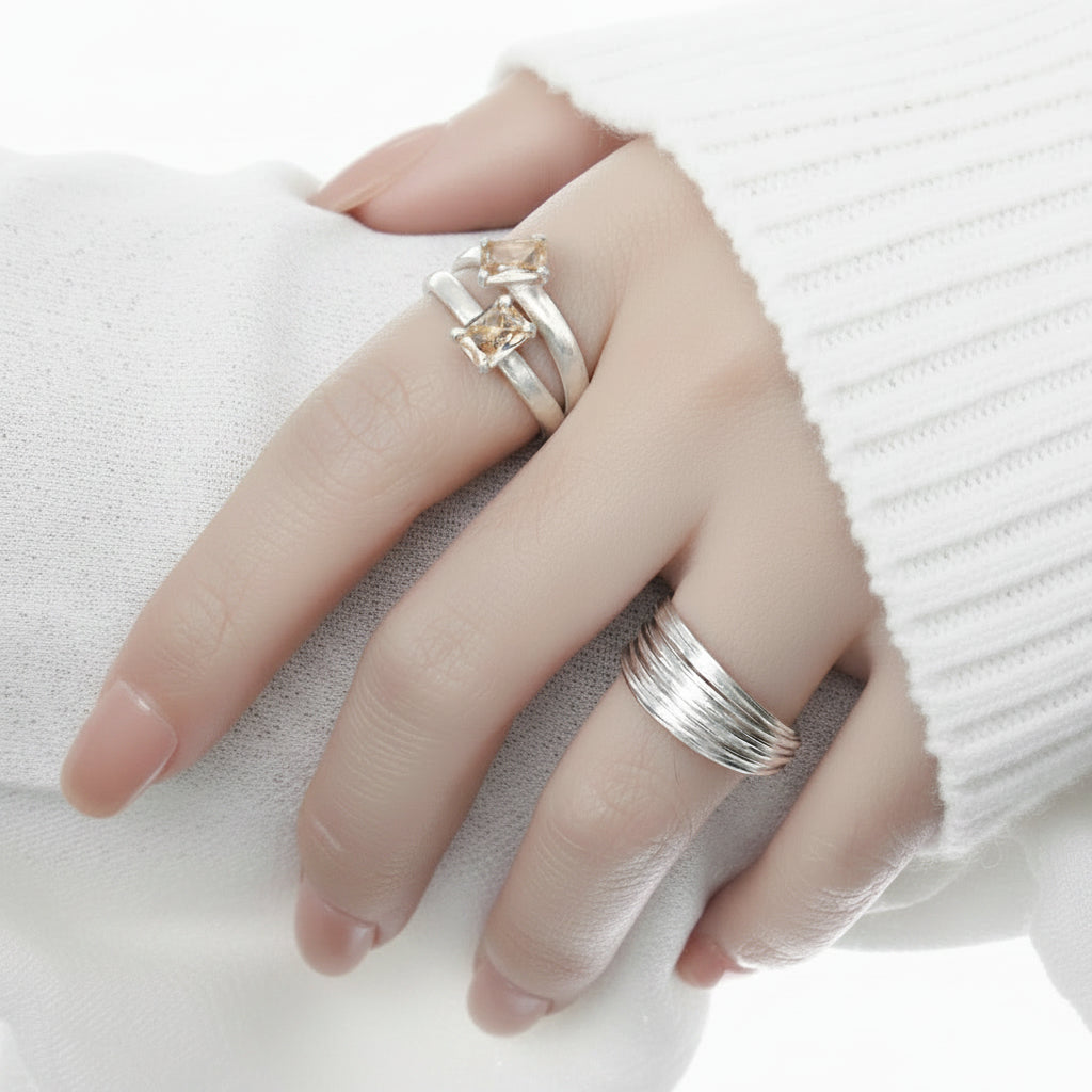 Hand wearing silver rings with a black background