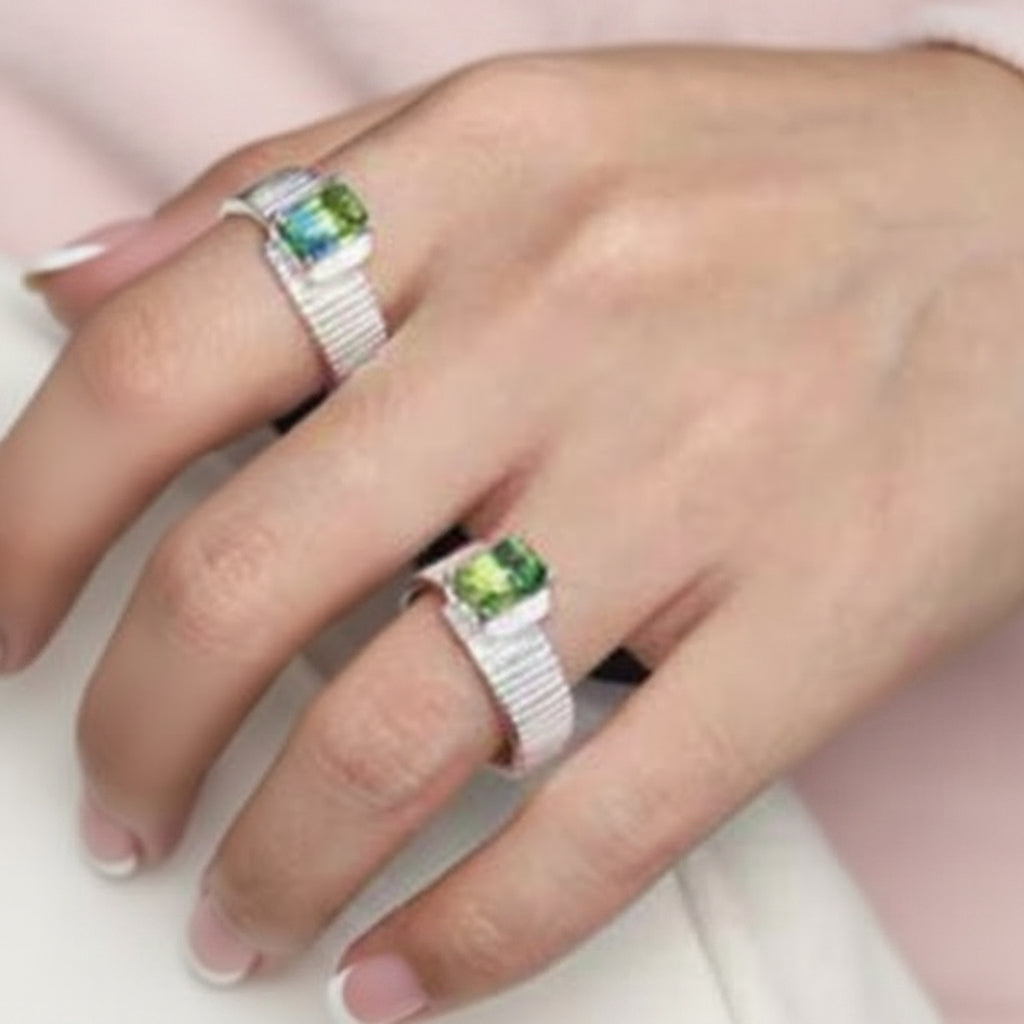 Close-up of a hand wearing two silver rings with green gemstones on a black background