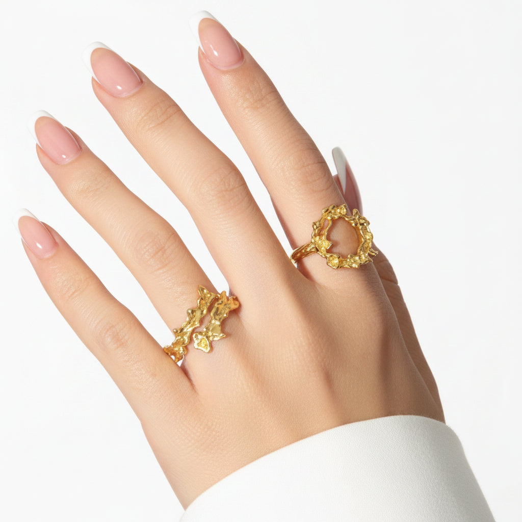 Hand wearing two gold rings with a black background